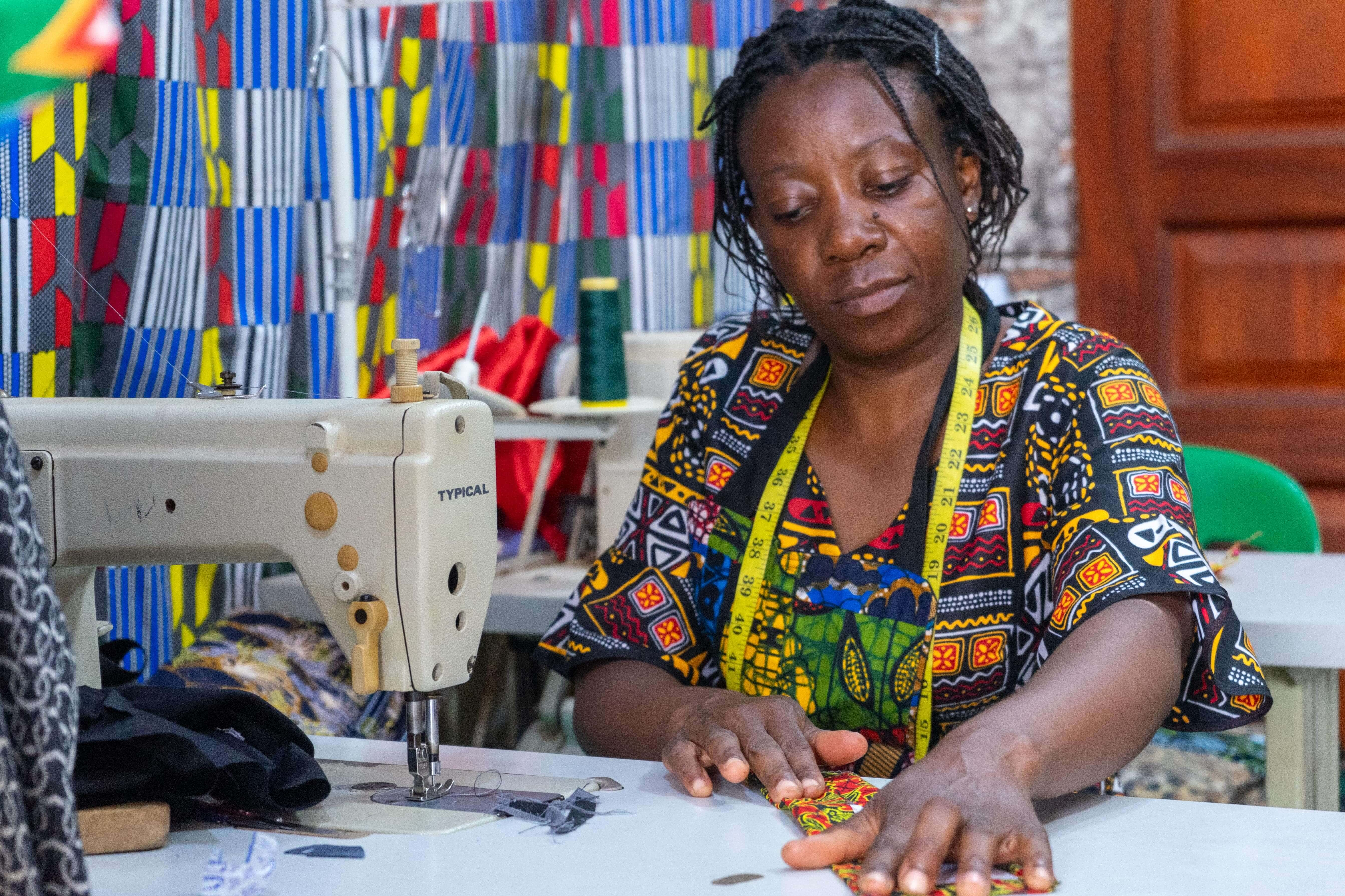 Riziki Kajabika at her sewing desk in Kampala. She received a business grant as part of the IRC’s Re:BUiLD Program Wave 1 RCTs grant, bought a sewing machine, fabric and paid rent for her shop.