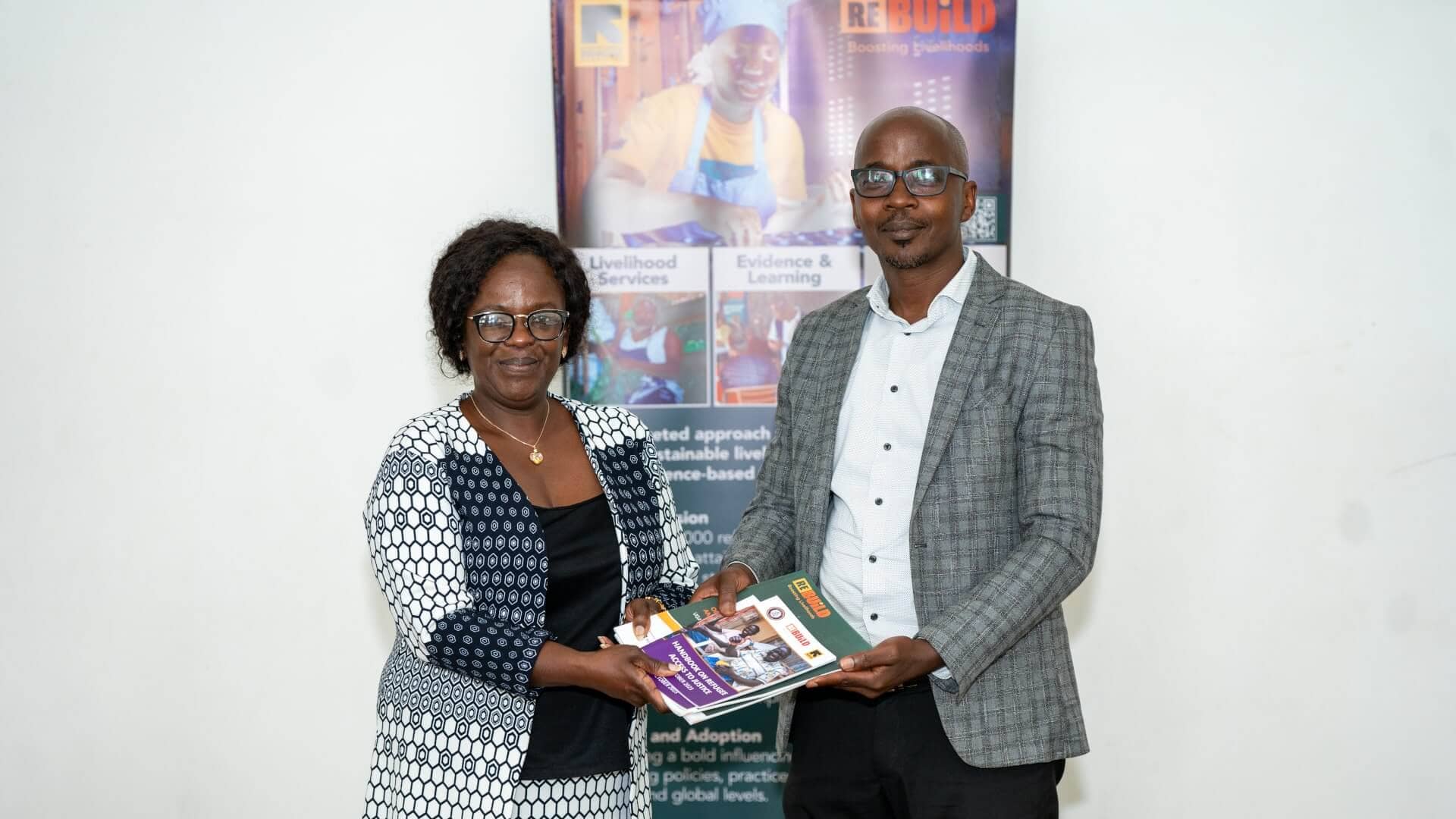 Re:BUiLD’s Program Director Priscilla Dembetembe hands Re:BUiLD IEC materials to Kampala City Council Authority’s Deputy Gender Director, Daniel Kaseregenyi.