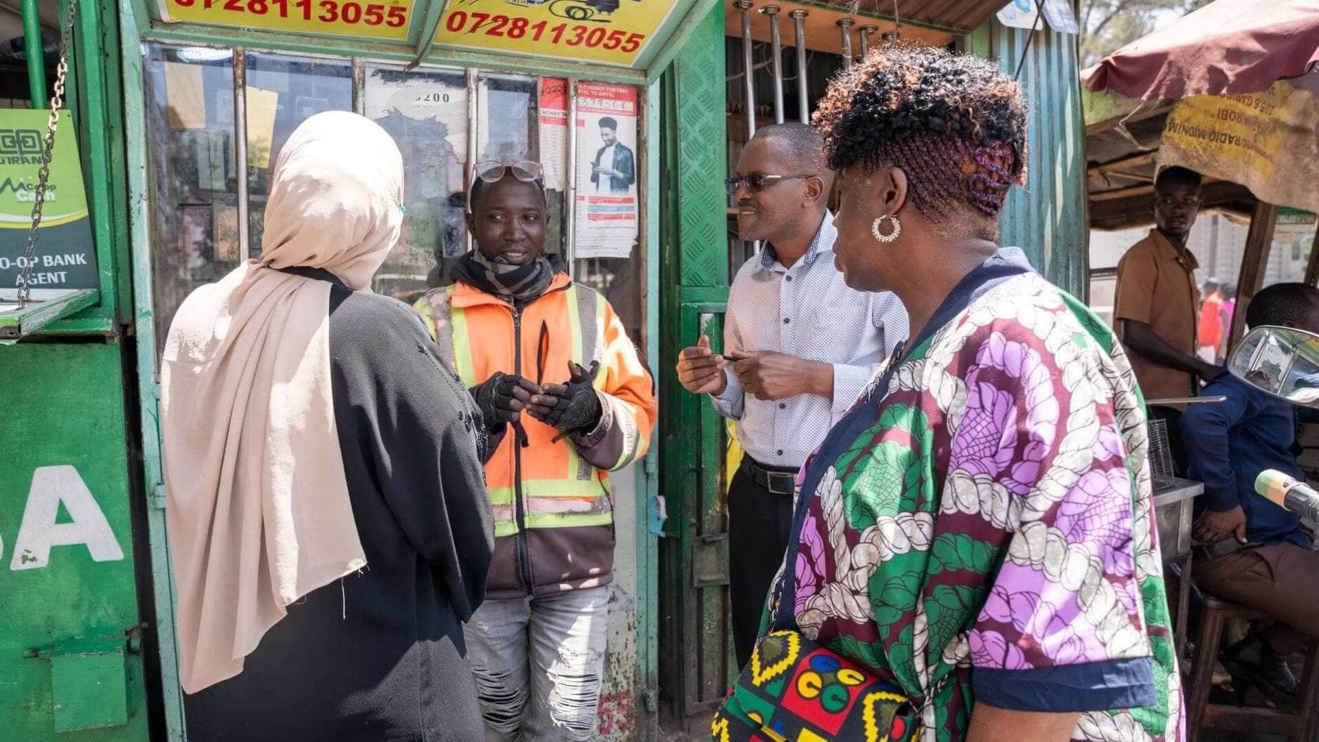 Dr. Lola Banjoko (right foreground), IRC UK Trustee Chair, interacts with Eric Ndikumana at his phone repair shop in Carlifornia Estate, Nairobi