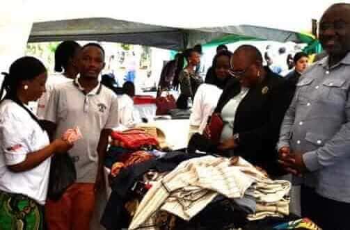 Justice Linda Mugisha Tumusiime (2nd Right), flanked by KCCA Deputy Executive Director Kigenyi Benon Moses (Right), buys a kitenge material from a ReBUiLD client during Labour Day Celebrations at KCCA