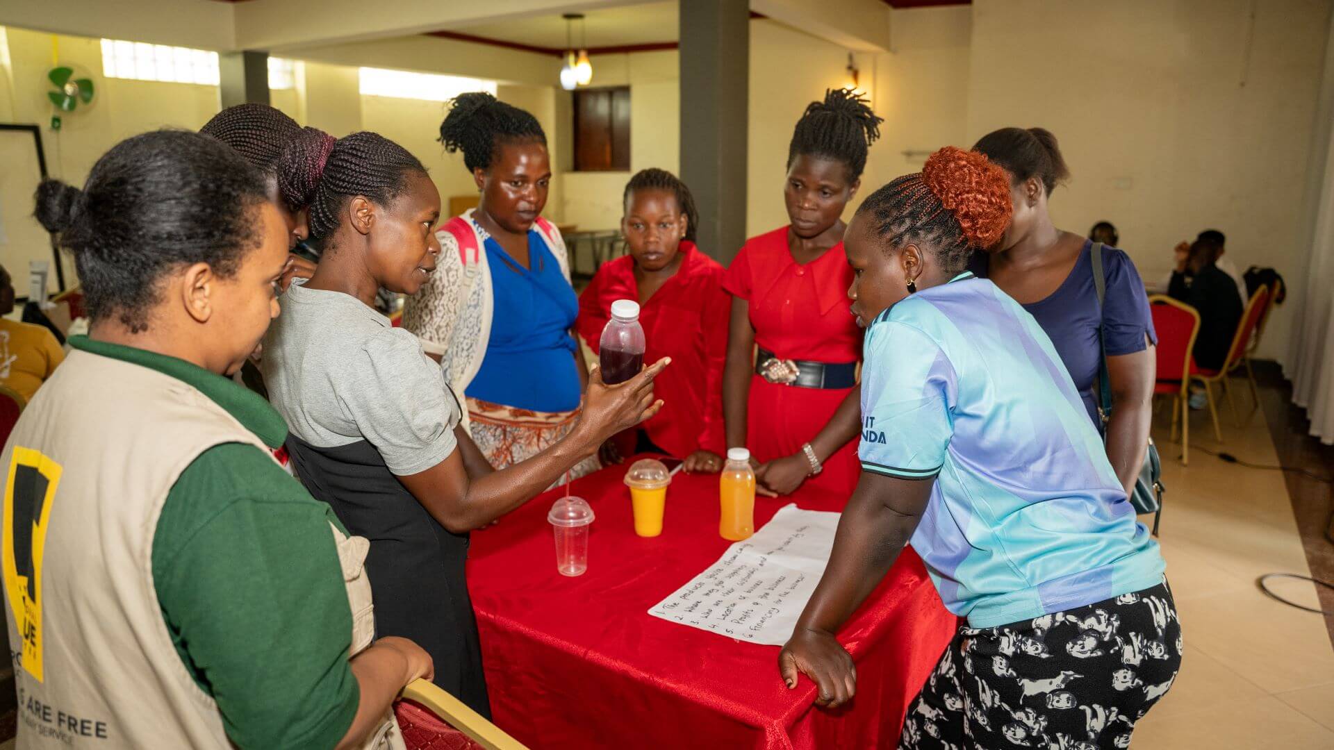 An entrepreneur participant presents juice samples from her business to other entrepreneurs during an RCT Wave 2 business fair session