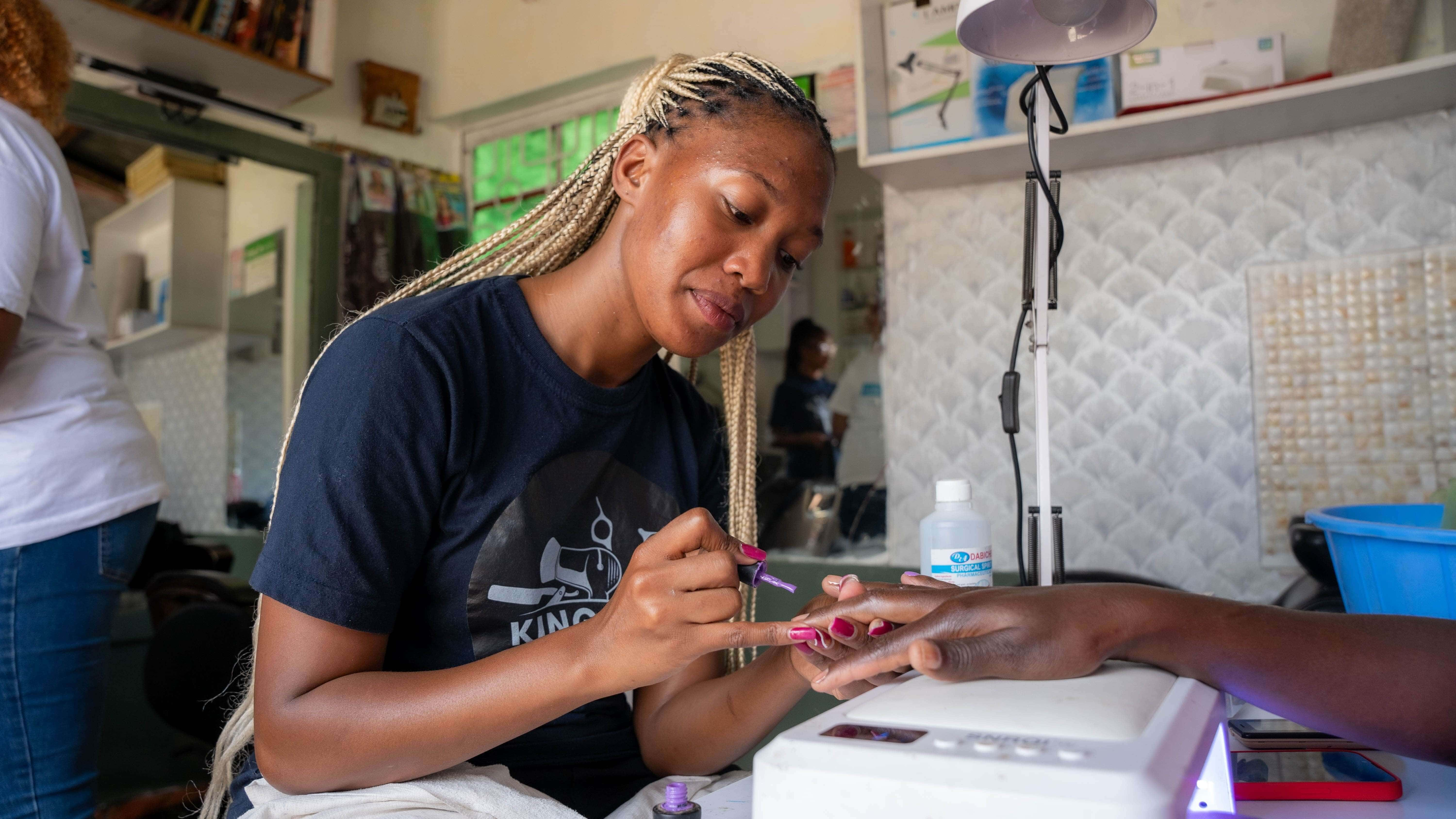 Mitchelle Nthambi applies gel polish to a client’s nails at her salon in Utawala. Mitchelle received a business grant  from the IRC & IKEA Foundation’s Re:Build program as part of microenterprise Randomized Controlled Trial (RCT) in Nairobi which helped her to expand her salon business. 